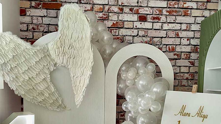 Weiße Engelsflügel und Ballondekoration für ersten Geburtstag
