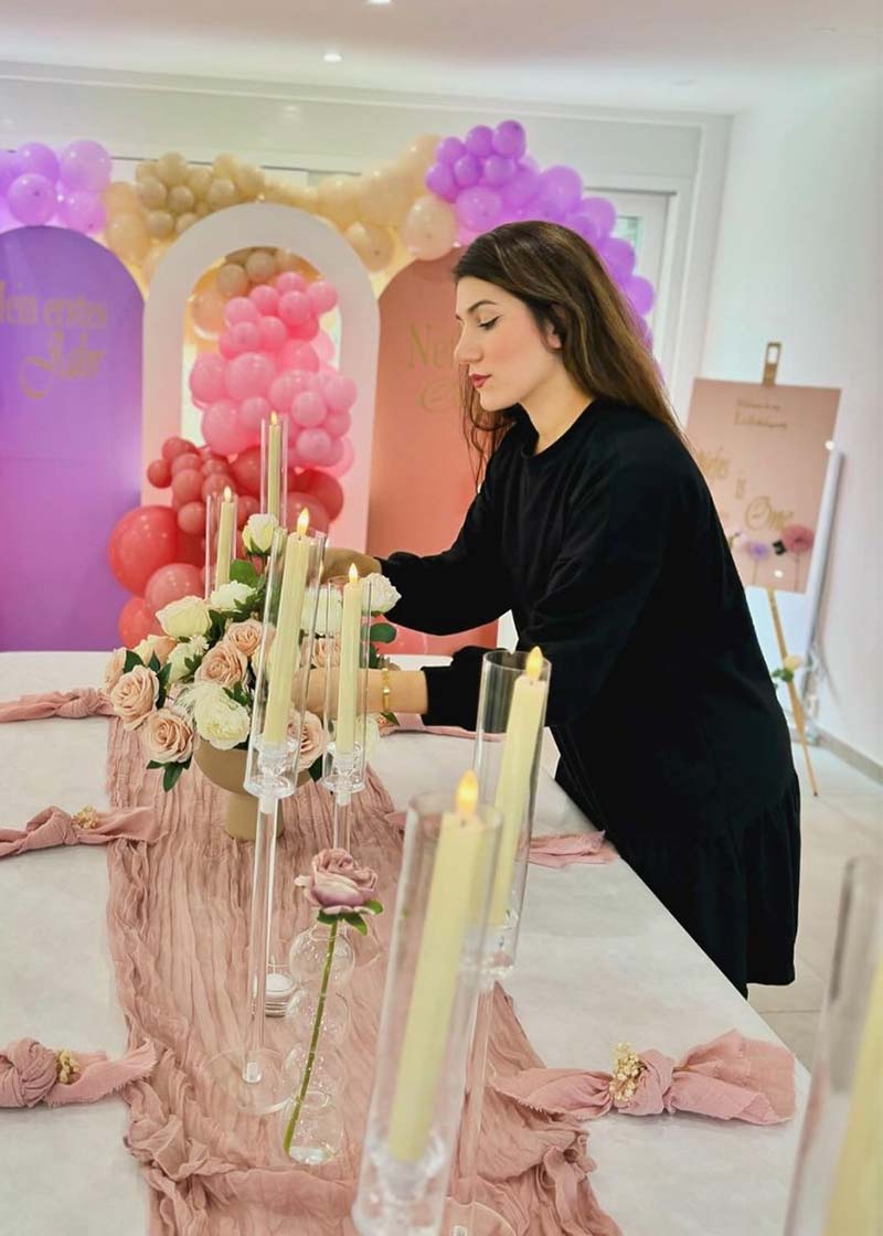 Melis dekoriert einen Tisch mit rosa Blumen und Kerzen